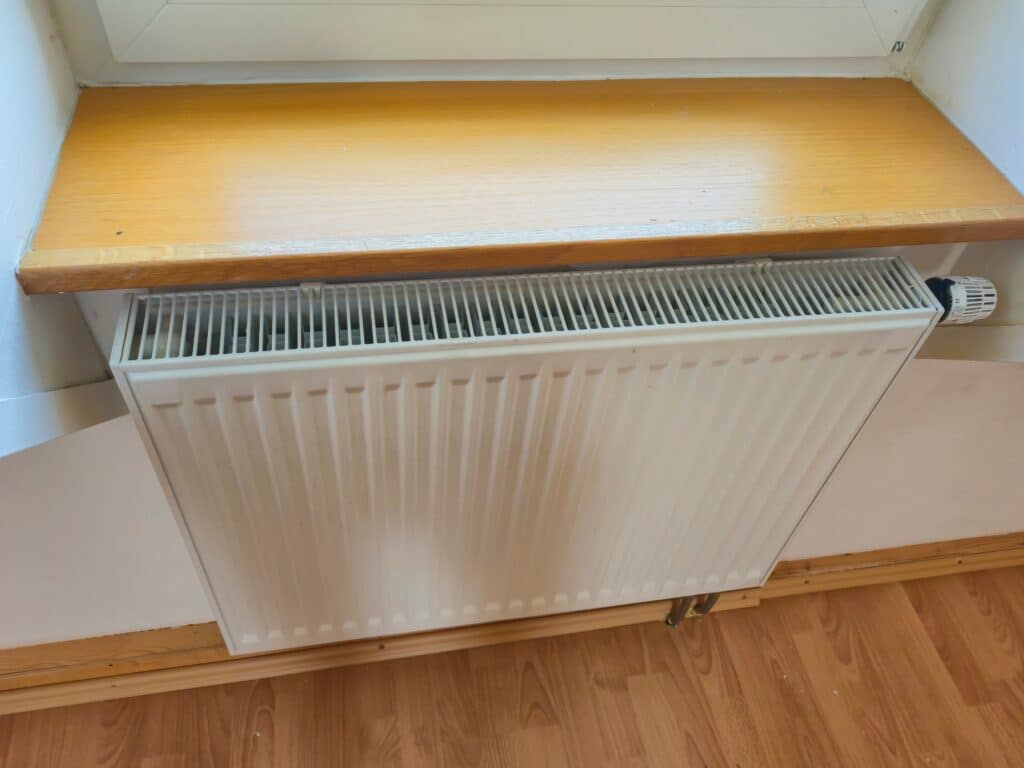 Modern,Radiator,Mounted,Beneath,A,Wooden,Shelf,,Providing,Heating,In